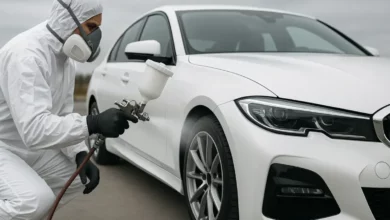На зображенні зображено біле авто, на якому технолог з фарбопультом готується нанести лакофарбове покриття.