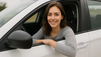 The image features a young woman sitting inside a car, partially leaning out of the driver’s side window.