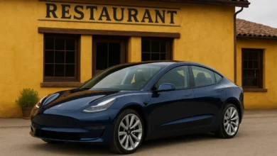 In the image, a sleek, modern electric vehicle is parked in front of a rustic restaurant with a yellow exterior.