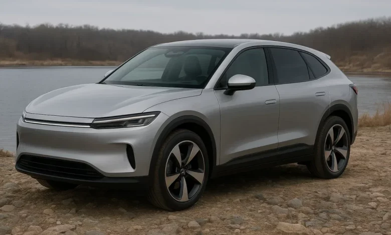 На зображенні зображено електричний SUV, що стоїть на кам'янистій місцевості біля водойми.