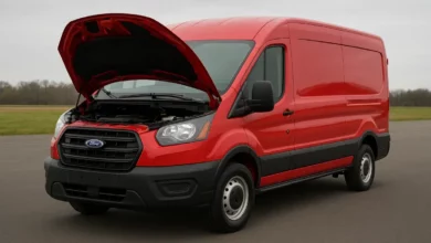 На зображенні видно декілька автомобілів, зокрема червоний фургон, який стоїть з відкритим капотом, на передньому плані.