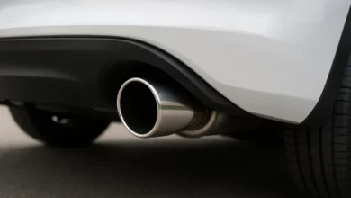 The image features a close-up view of a vehicle's exhaust pipe, positioned prominently in the foreground.