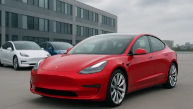 The image showcases a lineup of electric vehicles in a modern urban setting, with a prominent red sports car positioned in t…