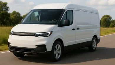 На зображенні зображено великий білий автономний мікроавтобус, що проїжджає по закругленій дорозі.