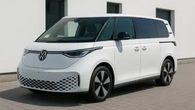 Зображення показує електричний мікроавтобус, розміщений на тротуарі біля будівлі з білими стінами.