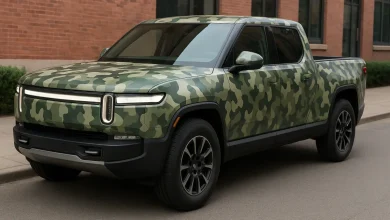 На зображенні представлений електропікап, частково покритий камуфляжною плівкою, що розташований на тротуарі в міському сере…