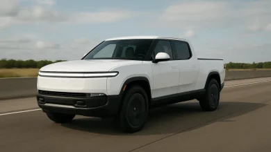 На зображенні зображена електровантажівка з гладким білим кузовом, яка рухається по шосе.